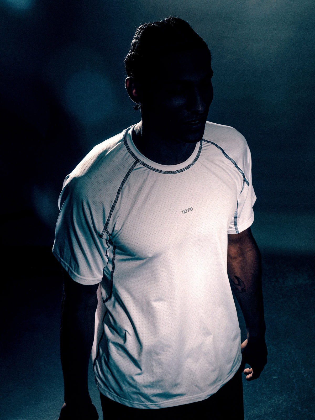 Athlete in the white TIOTIO Performance Tee, front view under low court light