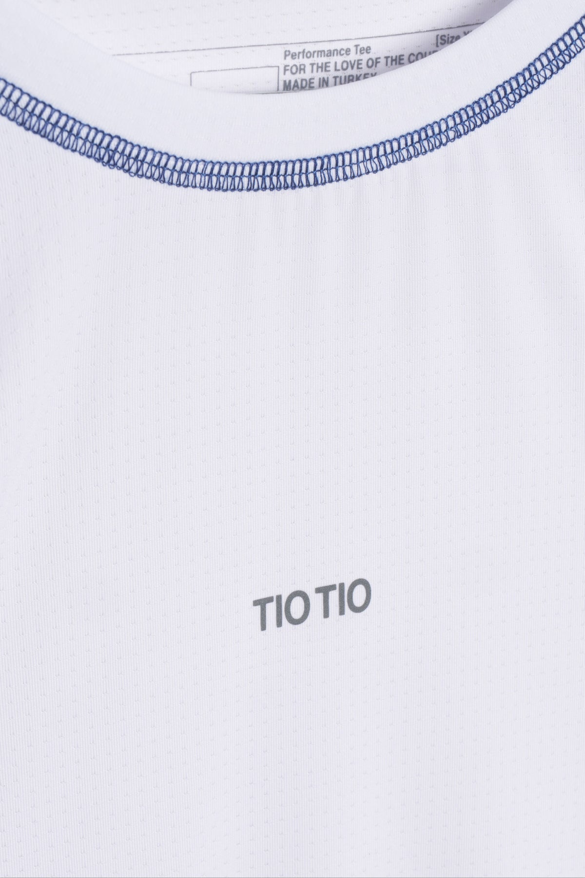 Neckline close-up showing blue contrast flatlock seams and the TIO TIO chest print